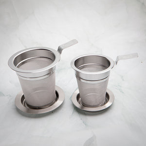 Two stainless steel tea strainers, sizes M and S, each with a flat handle and a dish, by Bettina's Tea